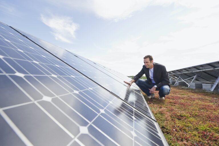 Germany, Munich, Man touching solar panel in solar plant